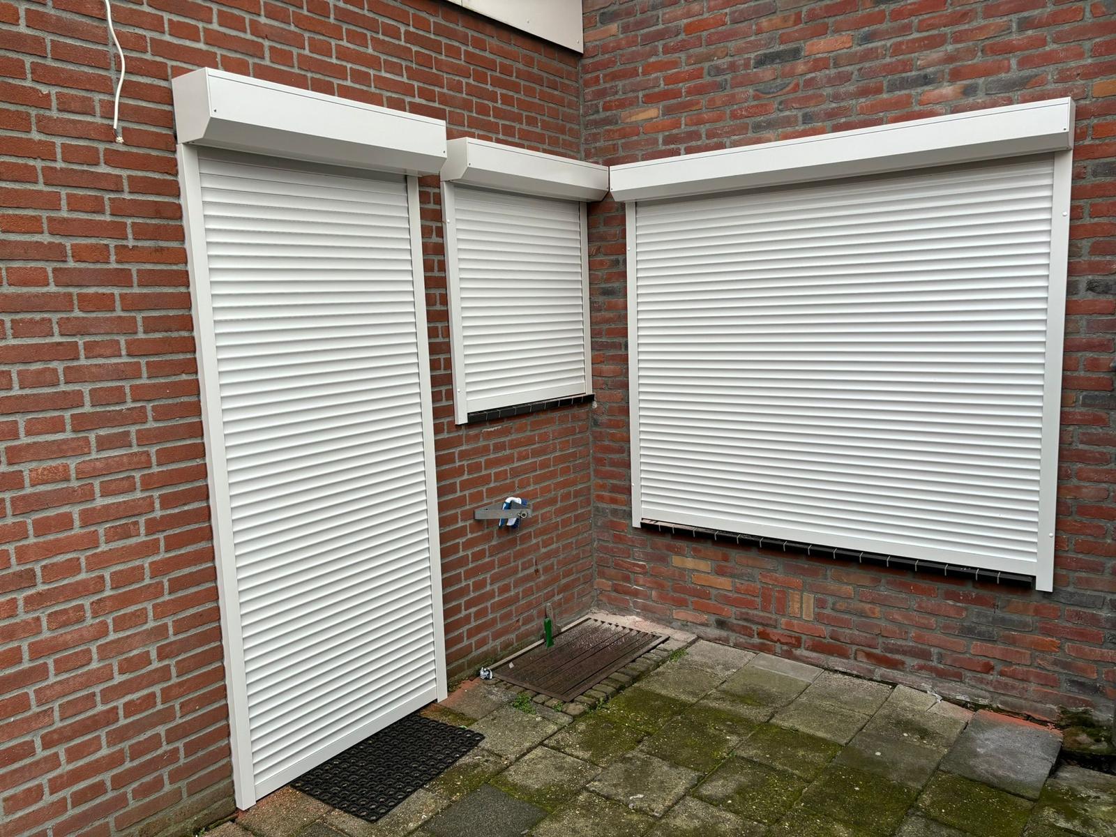 Witte rolluiken op maat aan de achtergevel van een woning