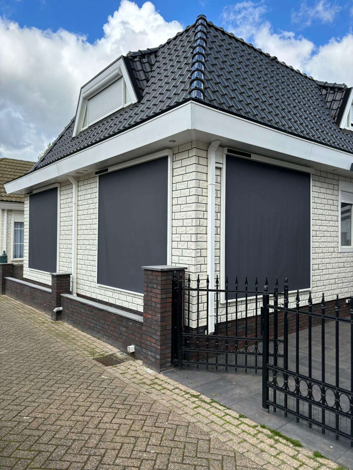 Antracietkleurige screens op de ramen van een witte woning